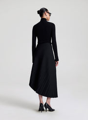 woman wearing black turtleneck and black pleated skirt