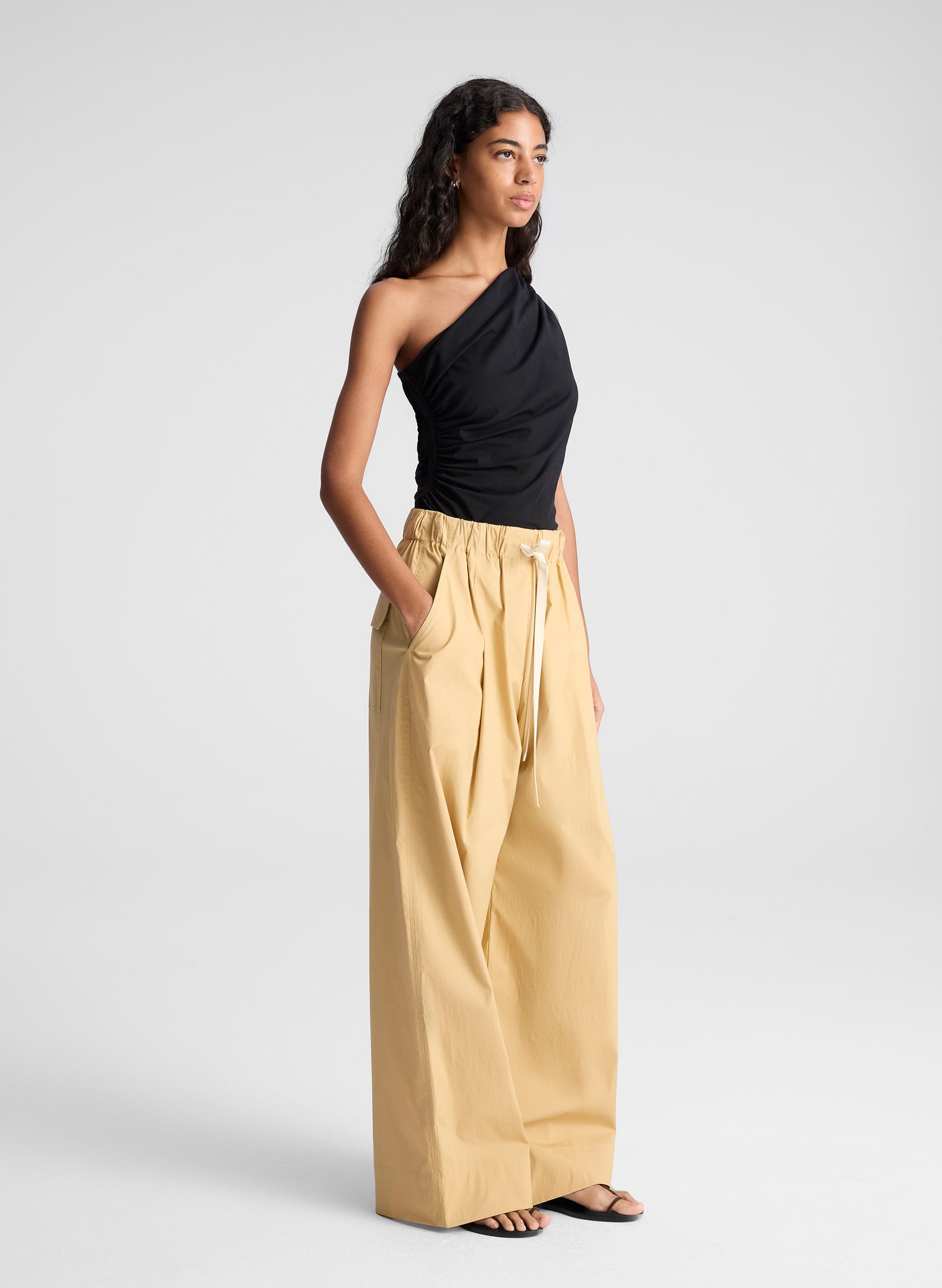 woman wearing one shoulder black tank and  tan wide leg pants
