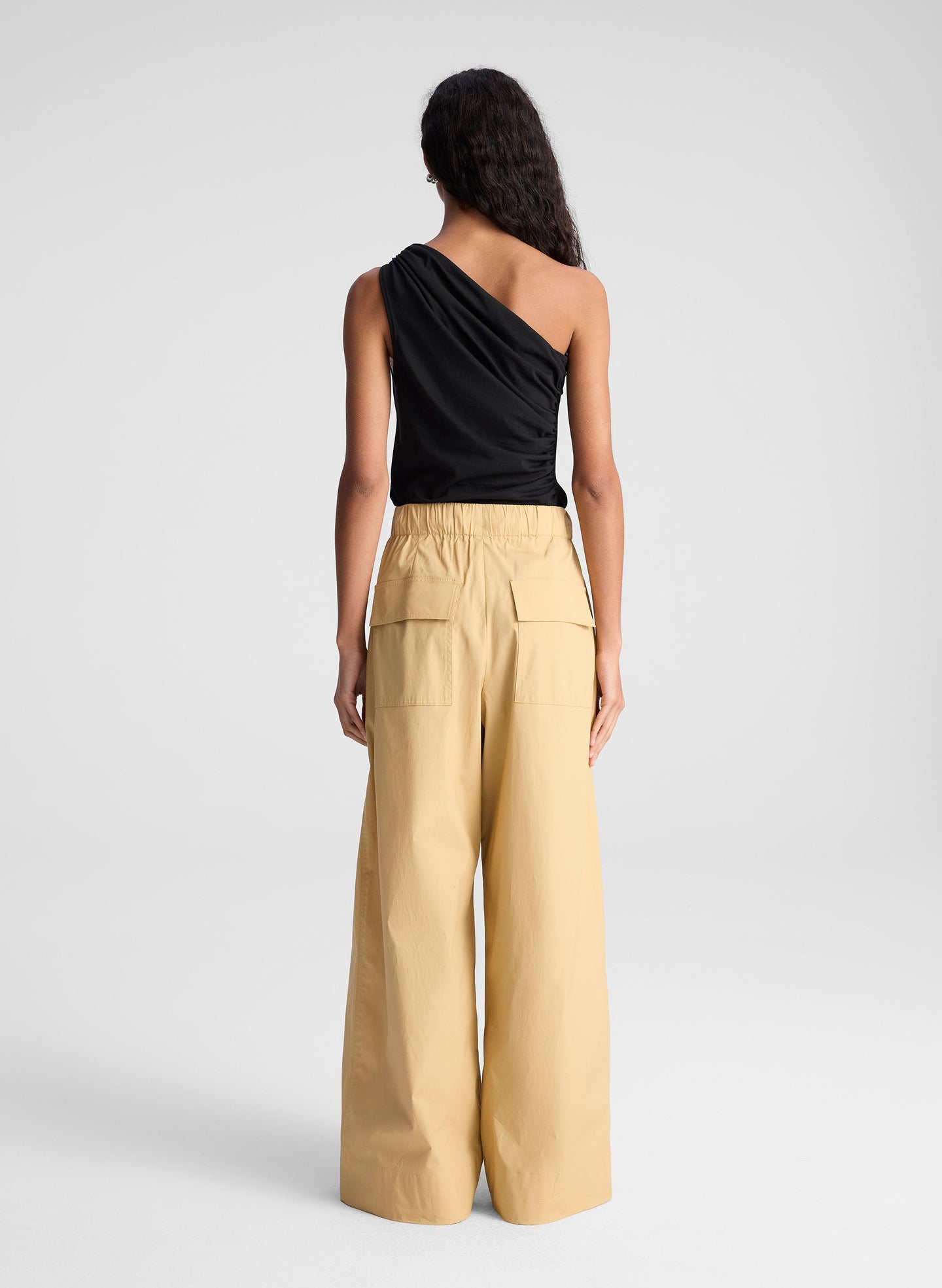 woman wearing one shoulder black tank and  tan wide leg pants