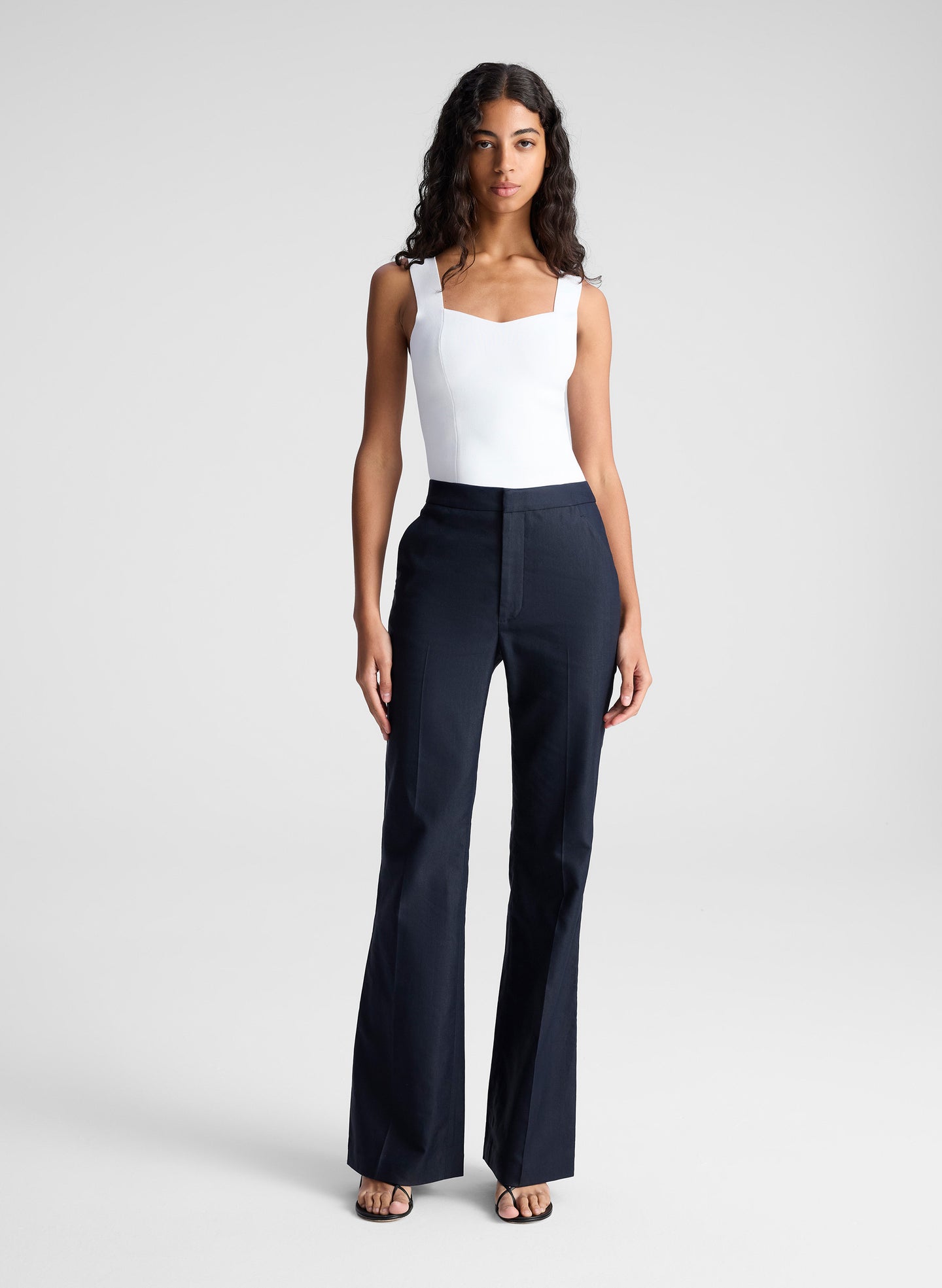 woman wearing white sleeveless top and navy blue pants