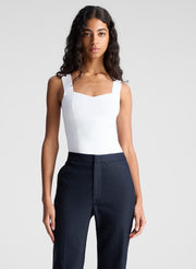 woman wearing white sleeveless top and navy blue pants