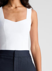 woman wearing white sleeveless top and navy blue pants