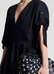 Person wearing a black dress with a plain background