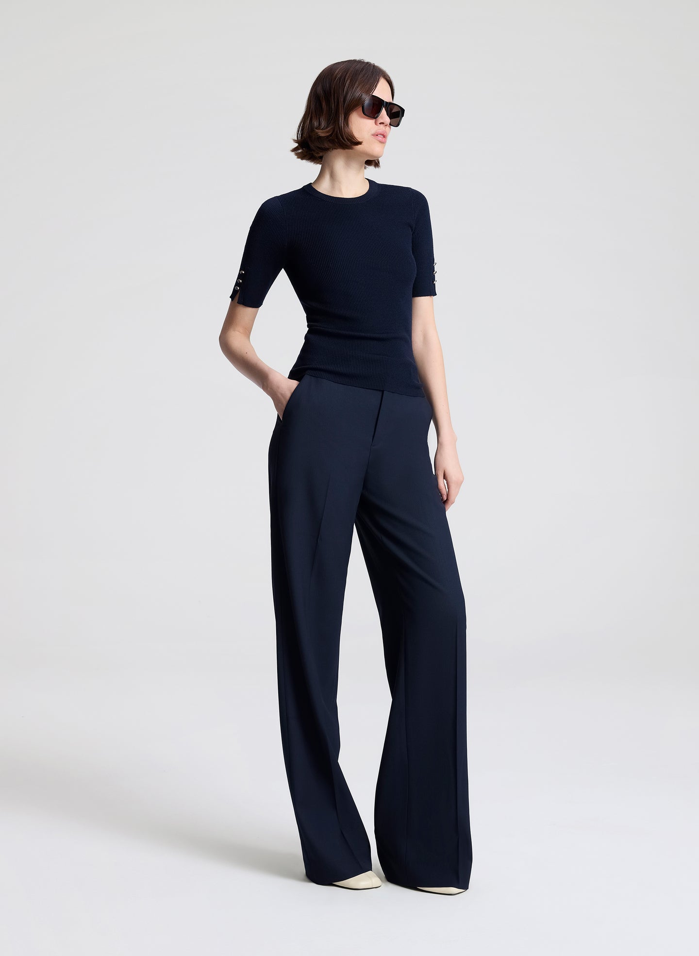 Woman wearing a navy outfit with a top and wide-leg pants on a white background