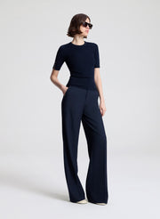 Woman wearing a navy outfit with a top and wide-leg pants on a white background