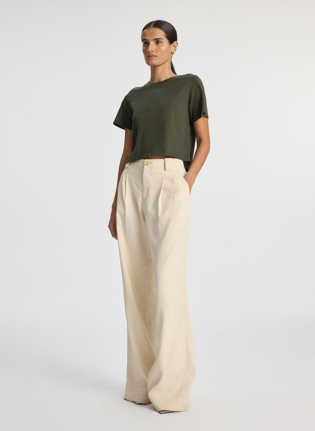 side view of woman wearing olive green short sleeve tshirt and beige wide leg pants