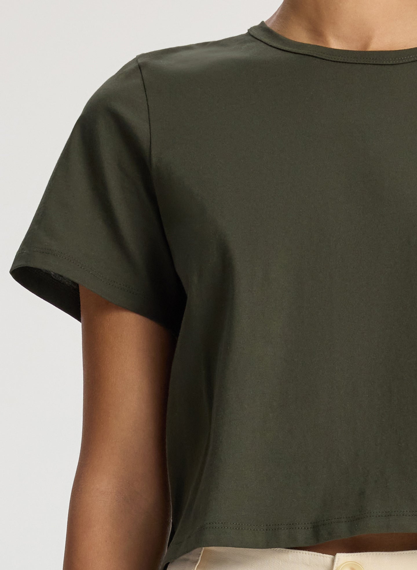 detail view of woman wearing olive green short sleeve tshirt and beige wide leg pants