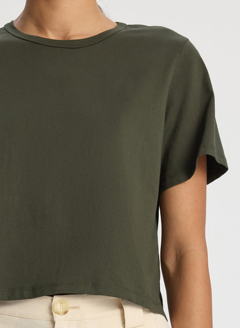 detail view of woman wearing olive green short sleeve tshirt and beige wide leg pants