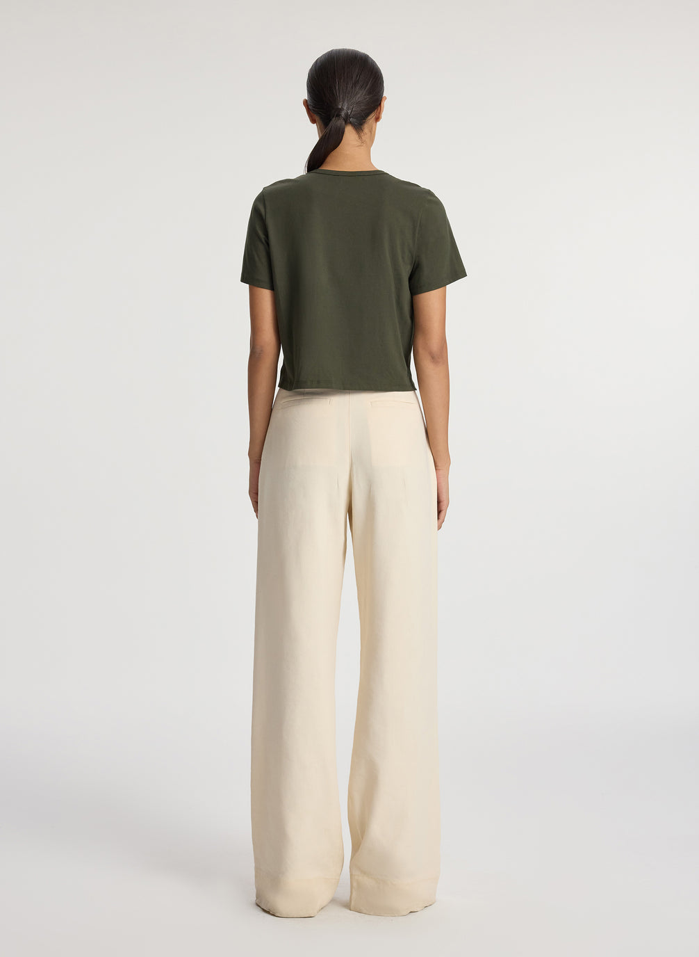 back view of woman wearing olive green short sleeve tshirt and beige wide leg pants