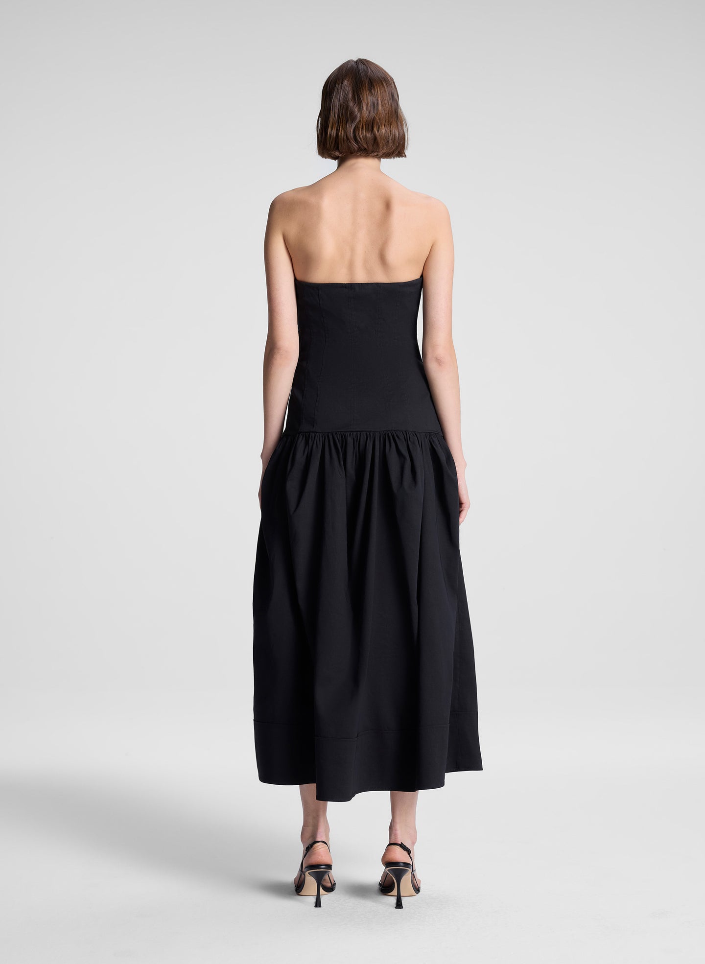 woman wearing black strapless drop waist midi dress