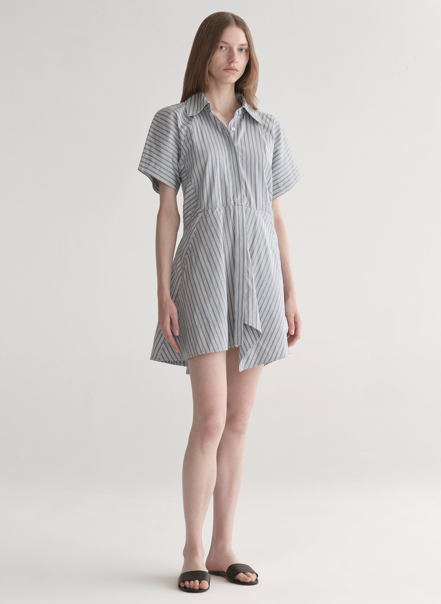 Woman wearing a striped shirt dress on a plain background
