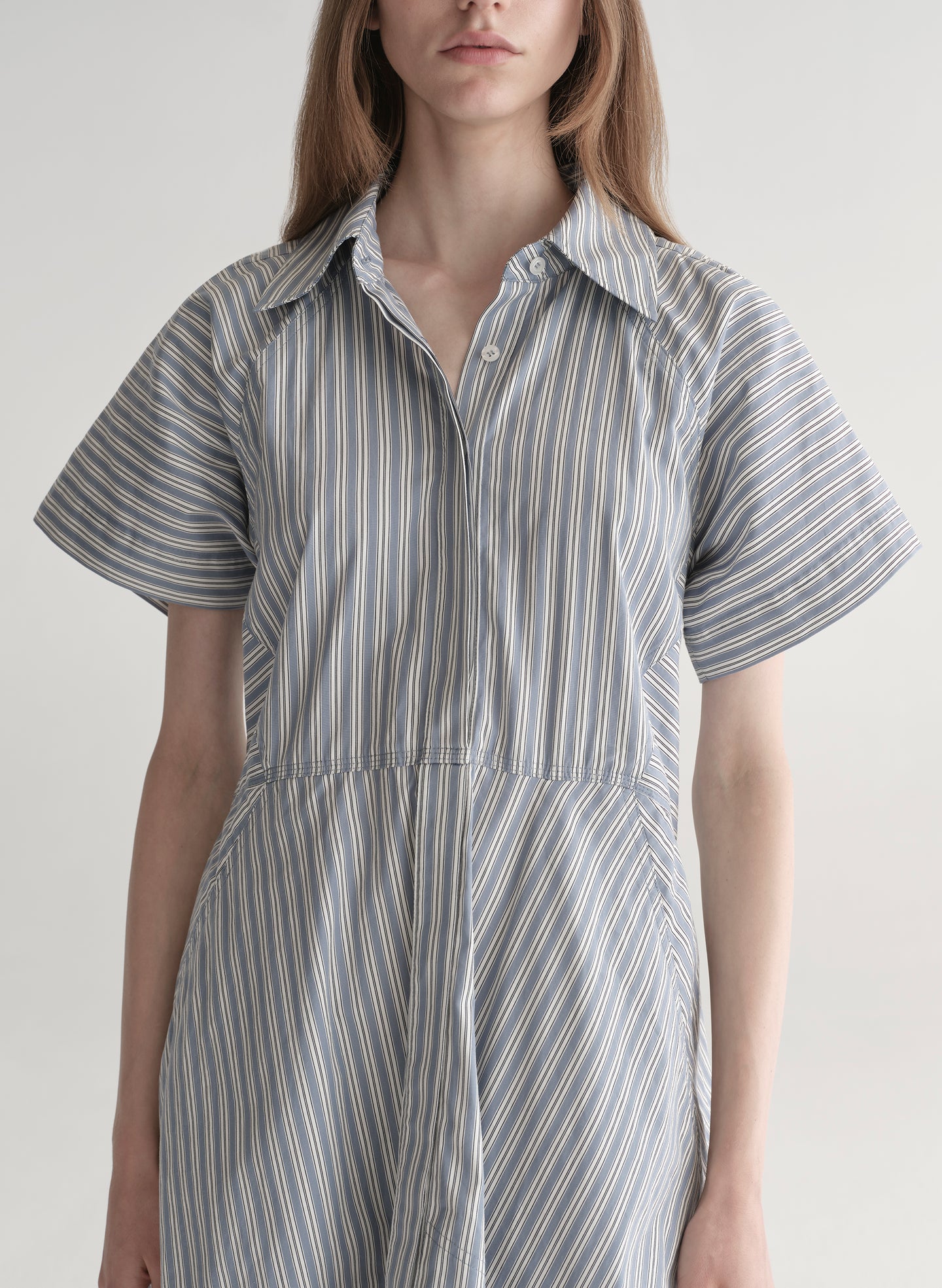 Woman wearing a striped shirt dress on a plain background