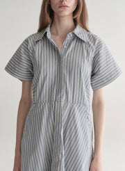 Woman wearing a striped shirt dress on a plain background