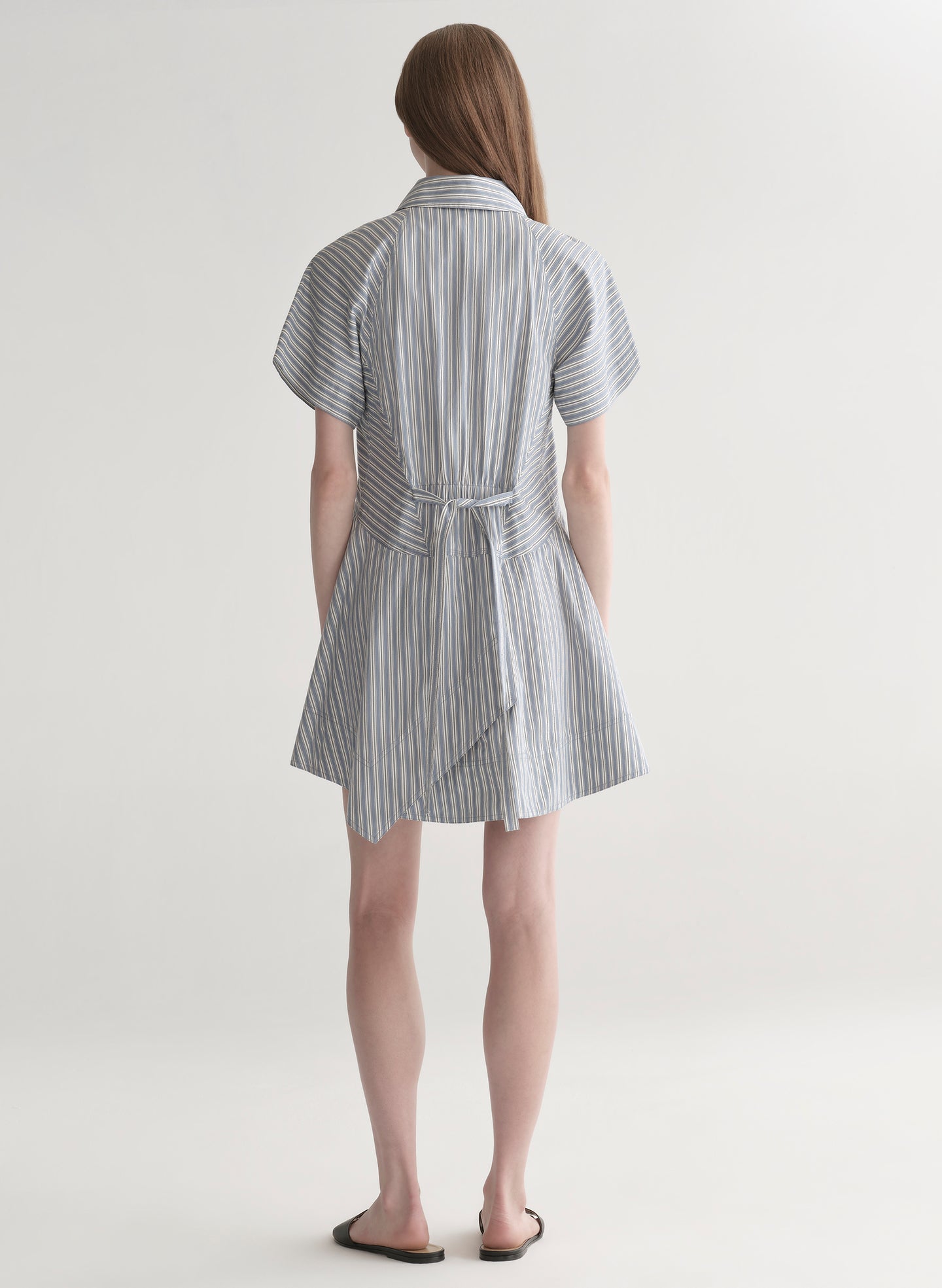 Woman wearing a striped shirt dress on a plain background