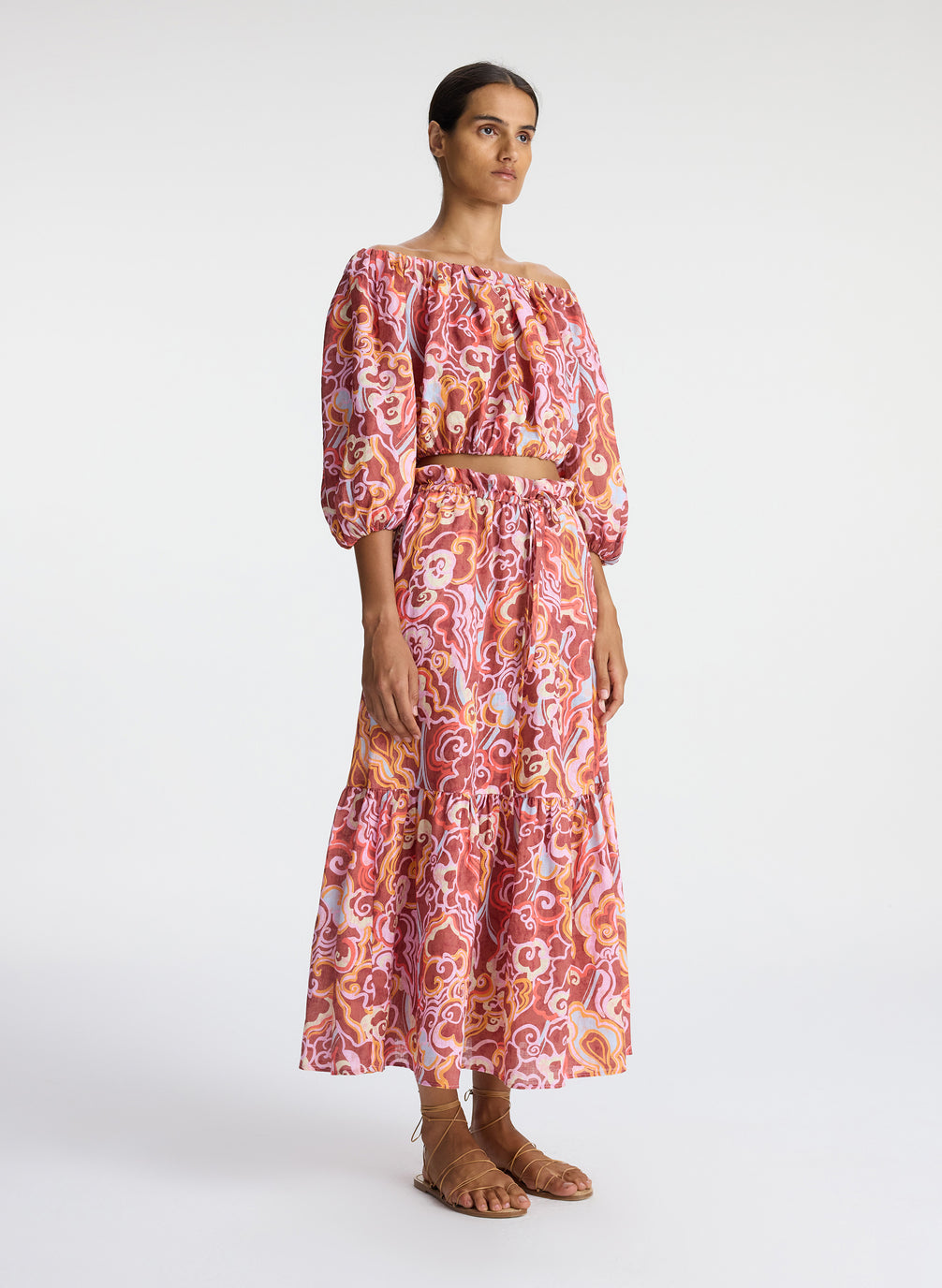 side view of woman wearing off shoulder printed linen top and matching midi skirt