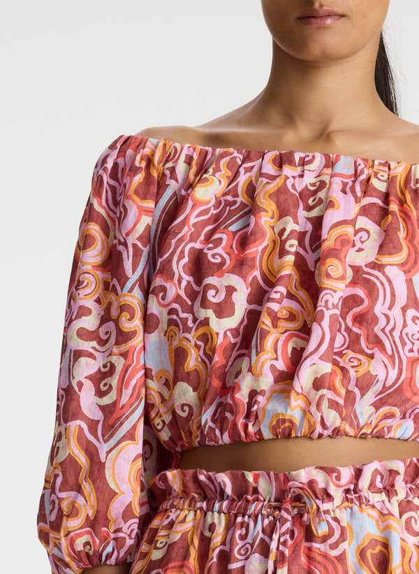 detail view of woman wearing off shoulder printed linen top and matching midi skirt
