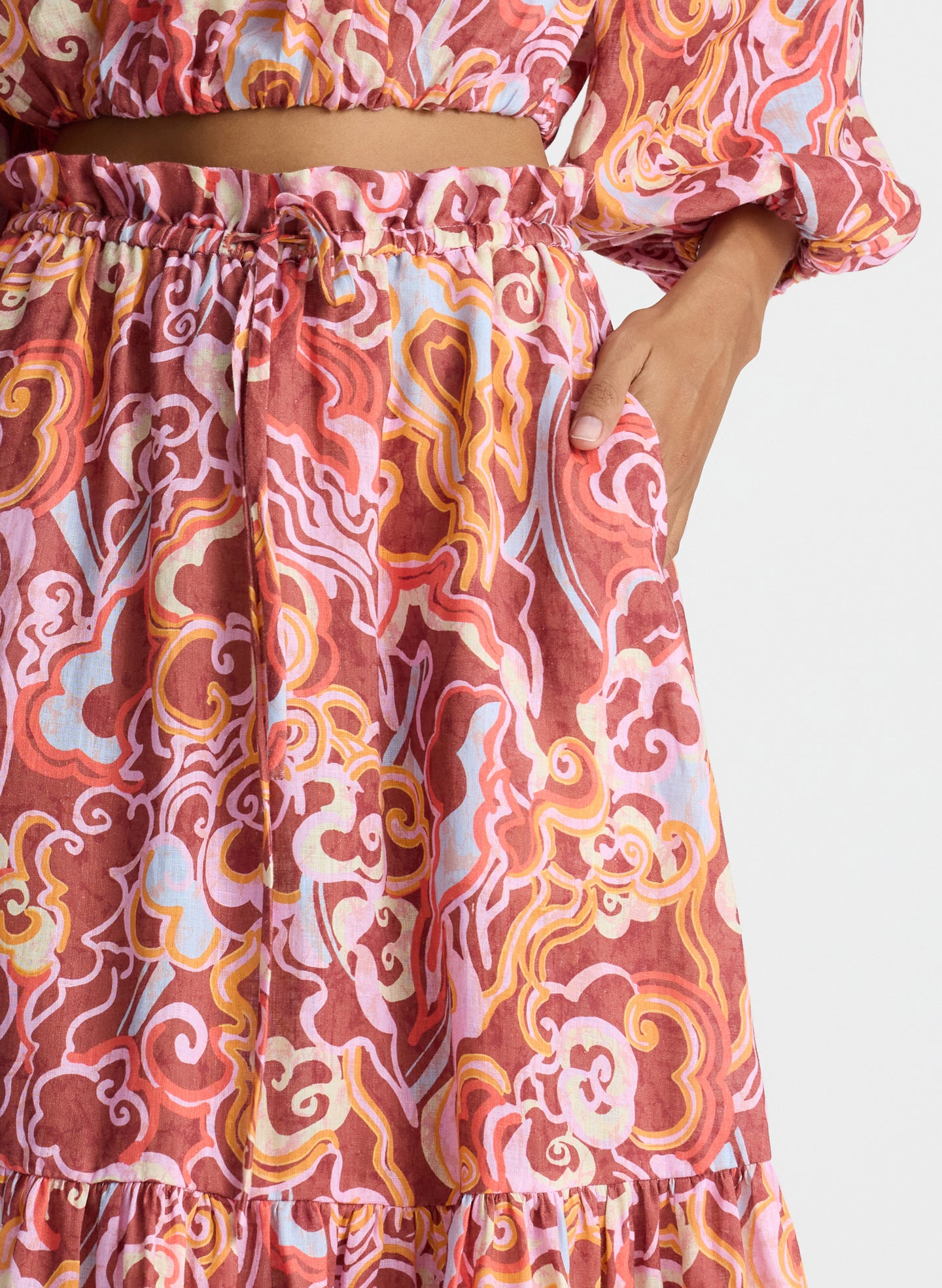 detail view of woman wearing magenta and orange abstract print off shoulder top and matching midi skirt