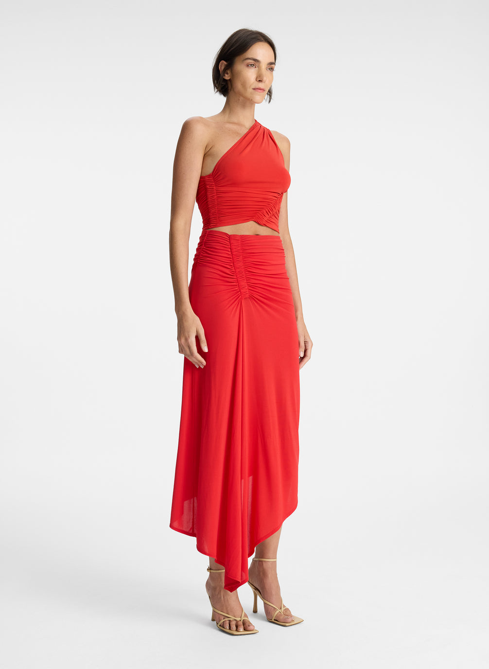 side view of woman wearing red one shoulder top and matching red skirt