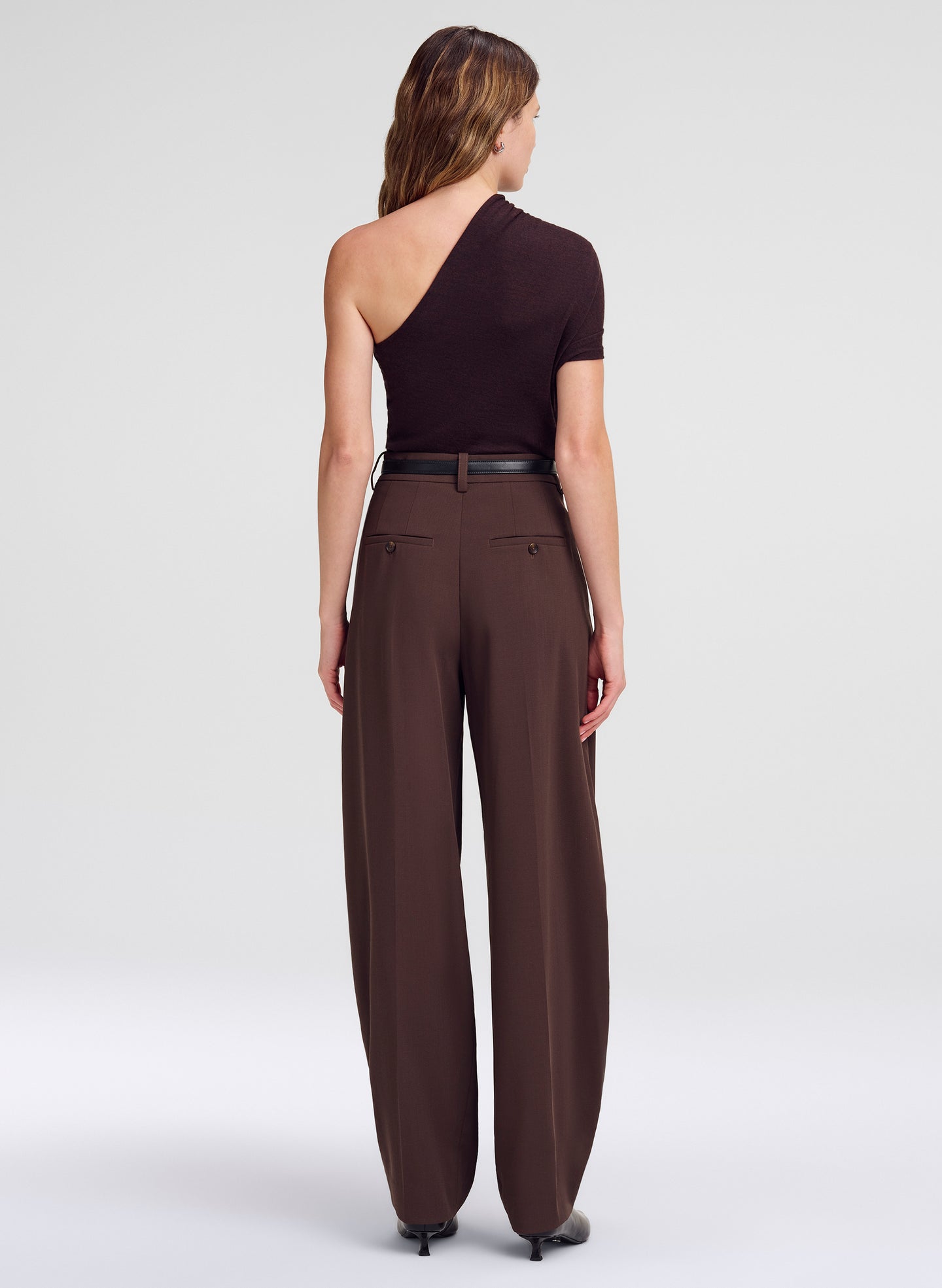 woman in one shoulder top and brown pants
