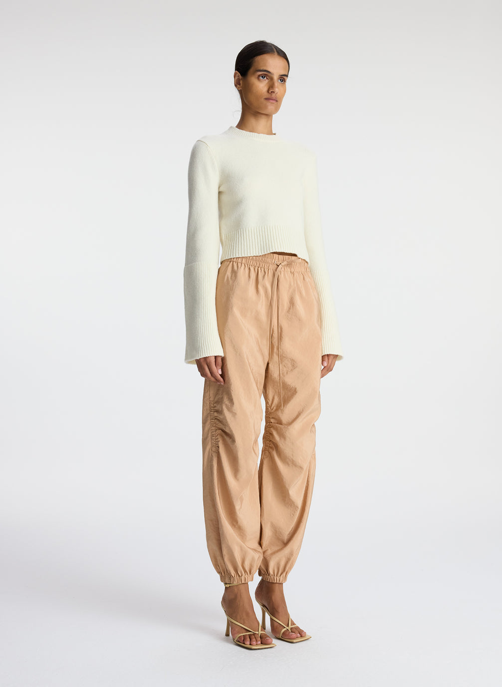 side view of woman wearing white sweater and beige nylon drawstring pants