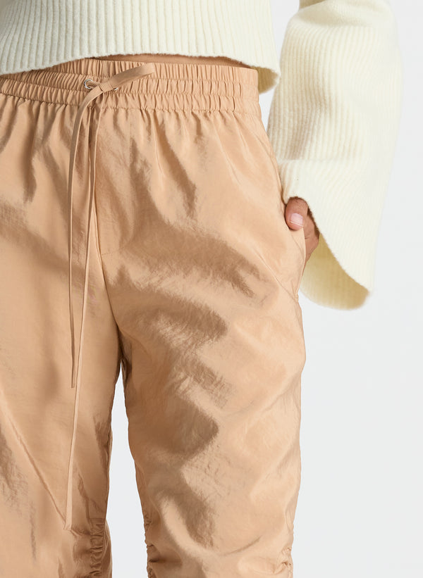 detail view of woman wearing white sweater and beige nylon drawstring pants