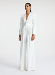 side view of woman wearing white long sleeve jumpsuit