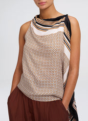 A sleeveless draped top with a beige, brown, and black geometric pattern and striped border details, shown on a model against a light gray background.