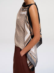 Woman wearing a patterned scarf on a plain background