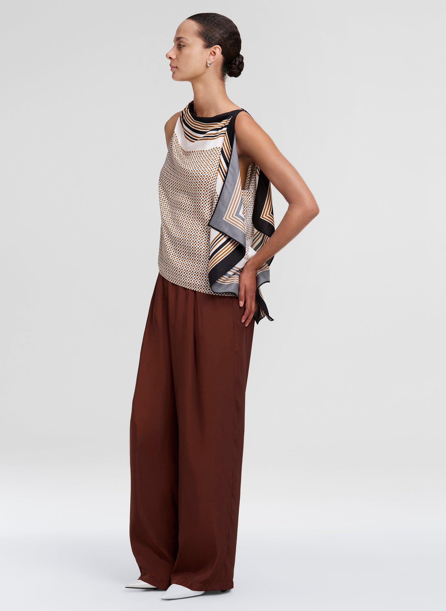 Woman wearing a sleeveless top with a patterned scarf and wide-leg pants on a white background