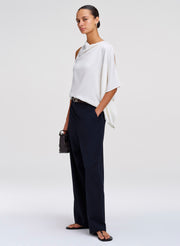 woman wearing white draped blouse and dark blue pants
