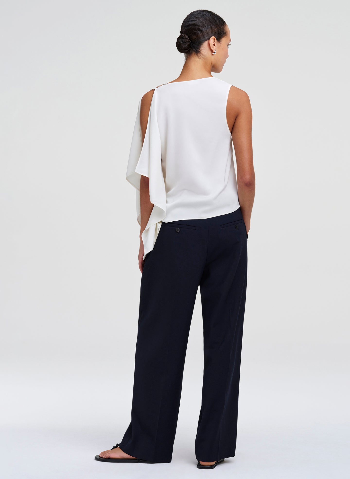 woman in draped white top and blue pants