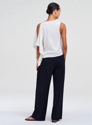 woman in draped white top and blue pants