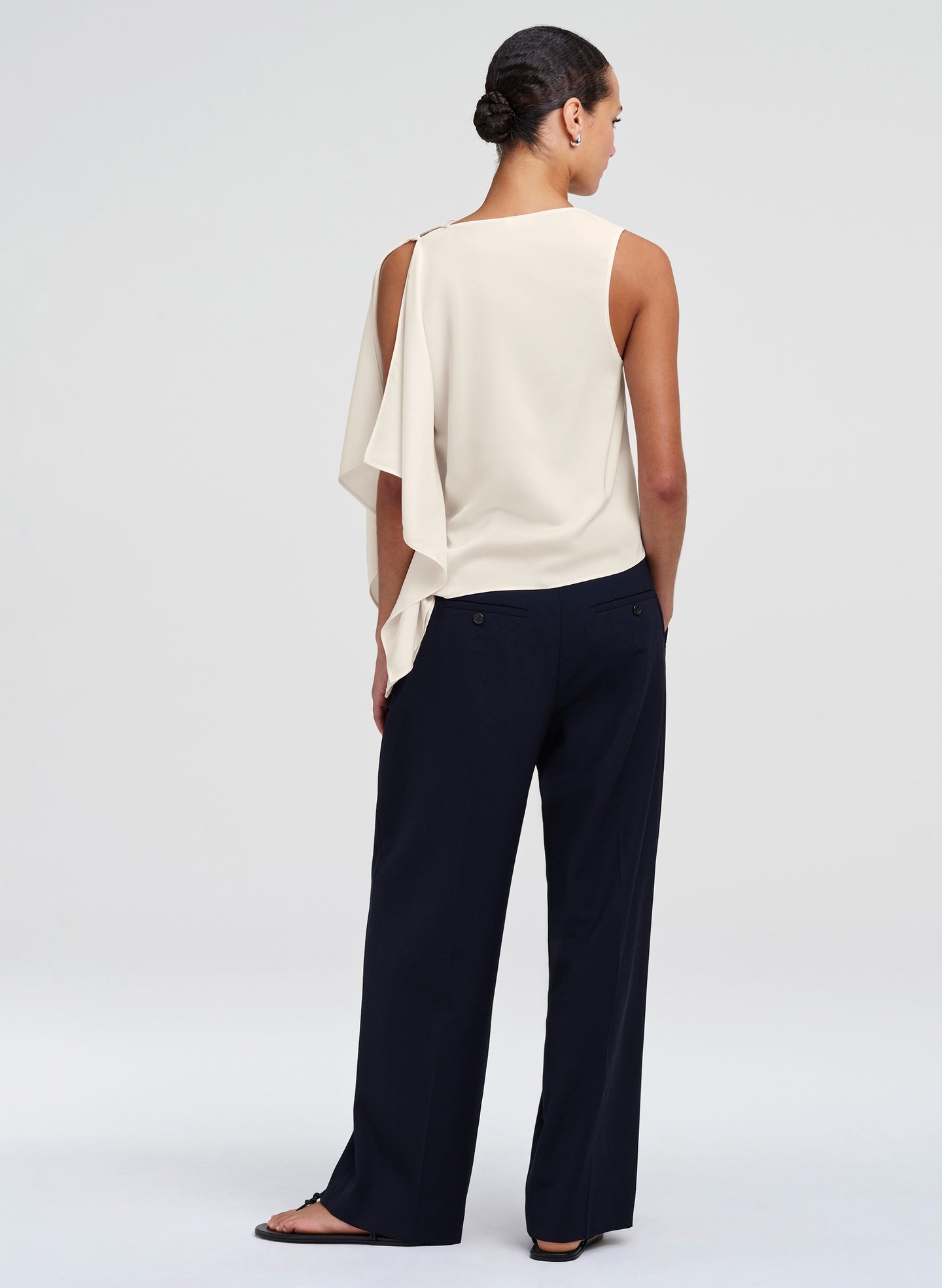 Woman wearing a white sleeveless top and blue pants on a white background