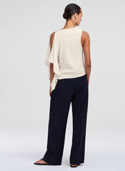 Woman wearing a white sleeveless top and blue pants on a white background