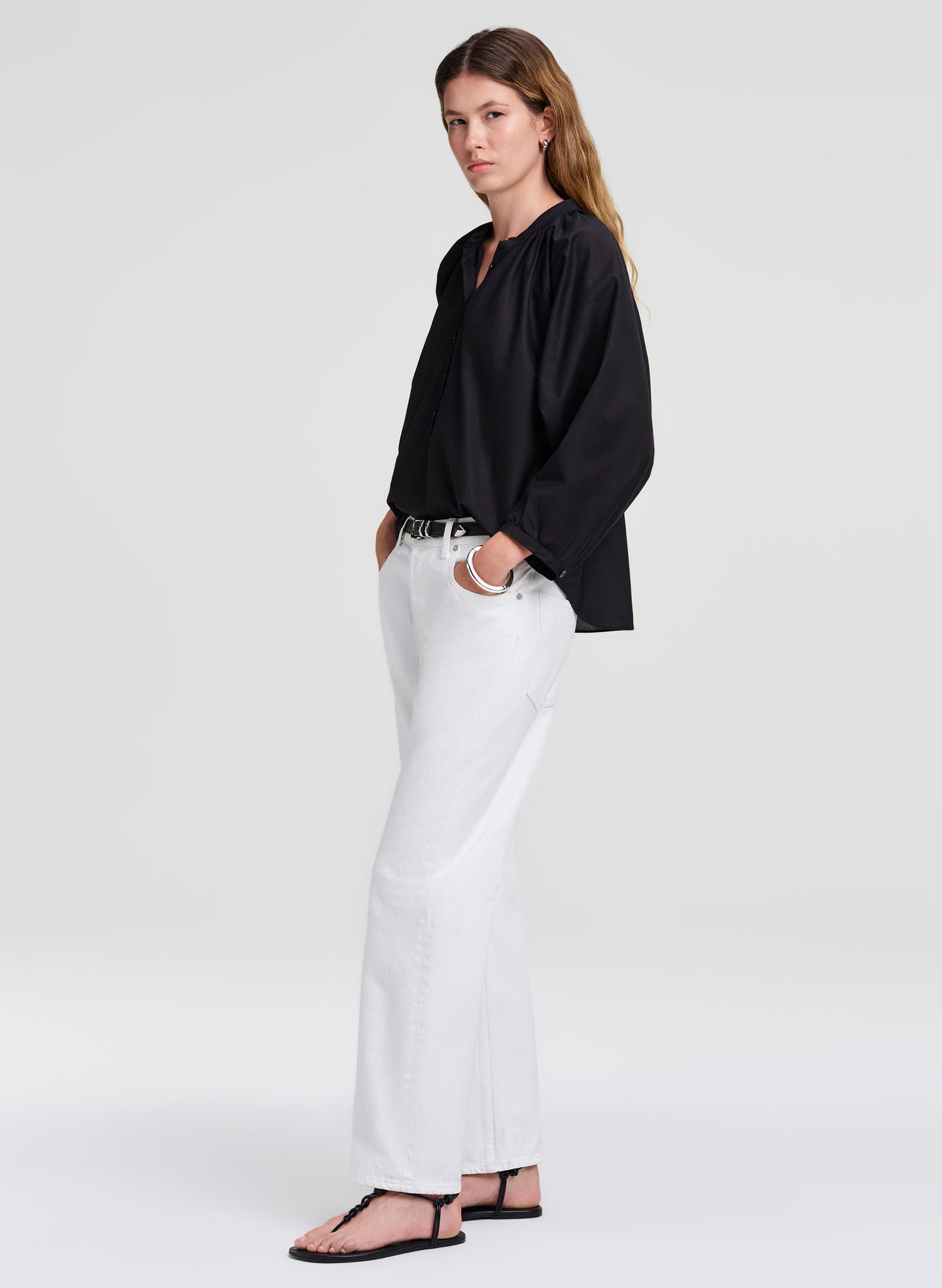 Woman wearing a black shirt and white pants on a plain background
