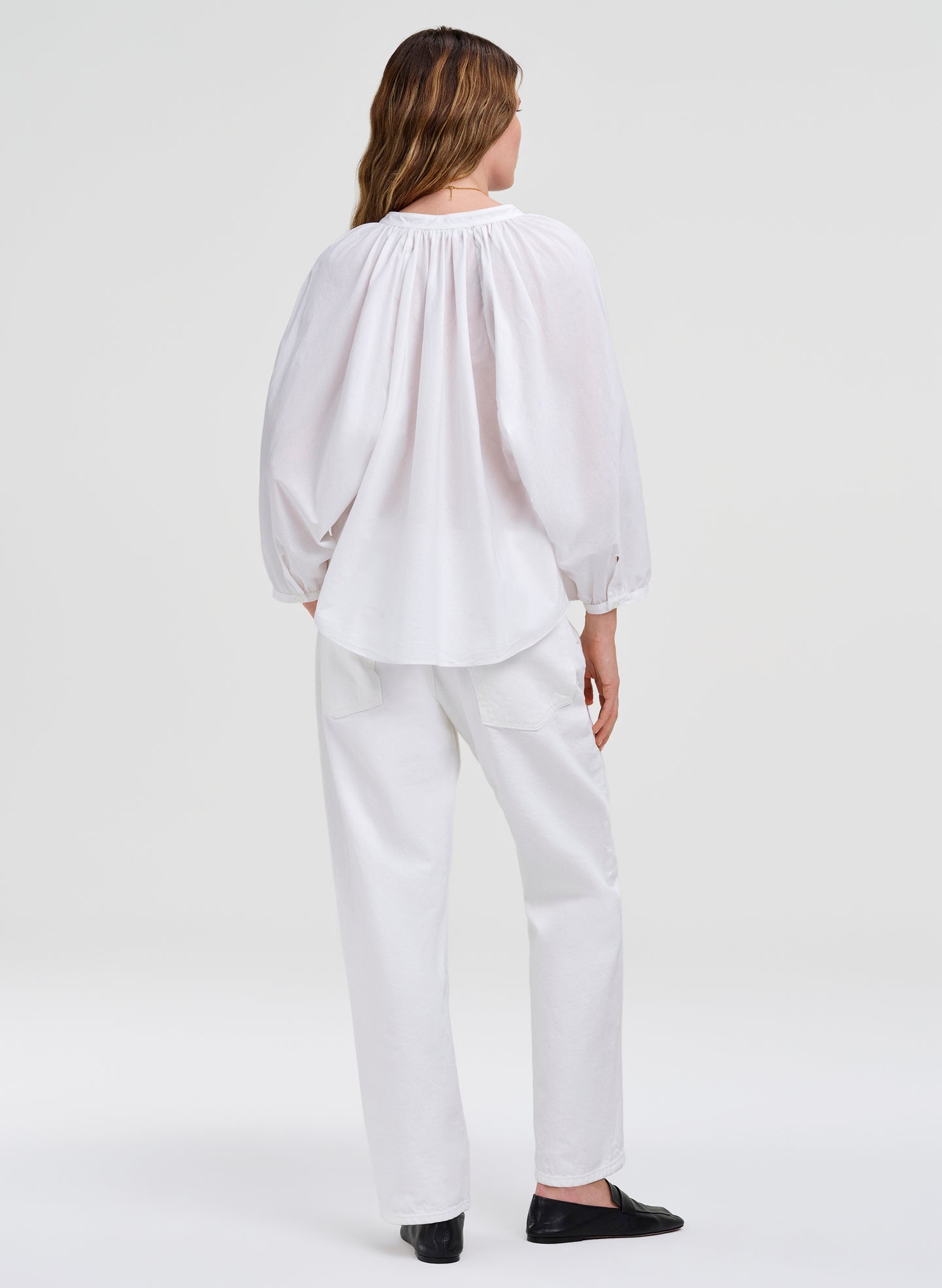 Person wearing a white blouse and pants on a white background
