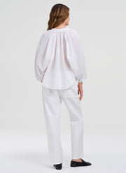 Person wearing a white blouse and pants on a white background