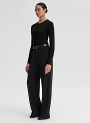 Person wearing a black long-sleeve top and black pants on a white background