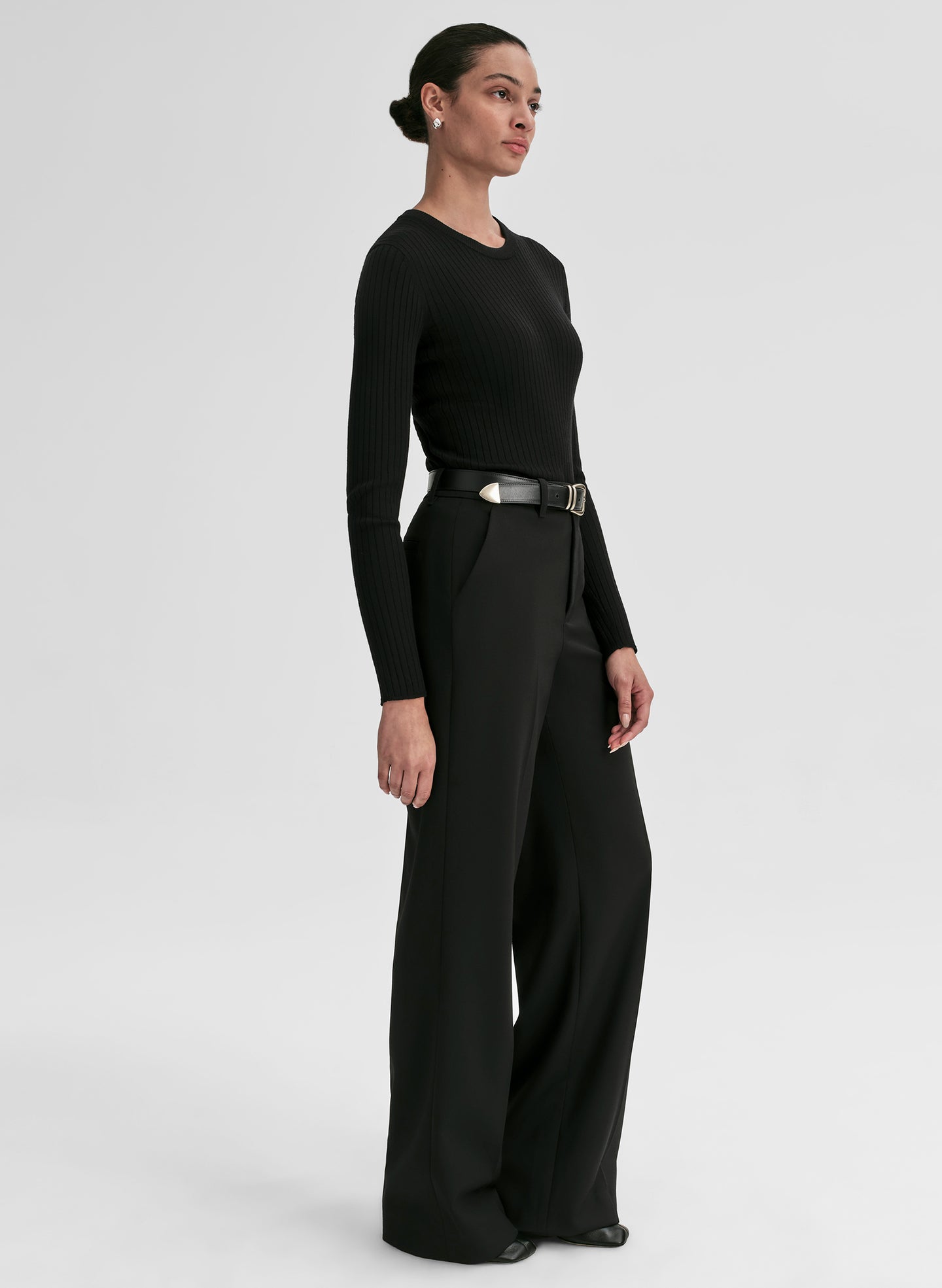 Woman wearing a black outfit with wide-leg pants on a white background
