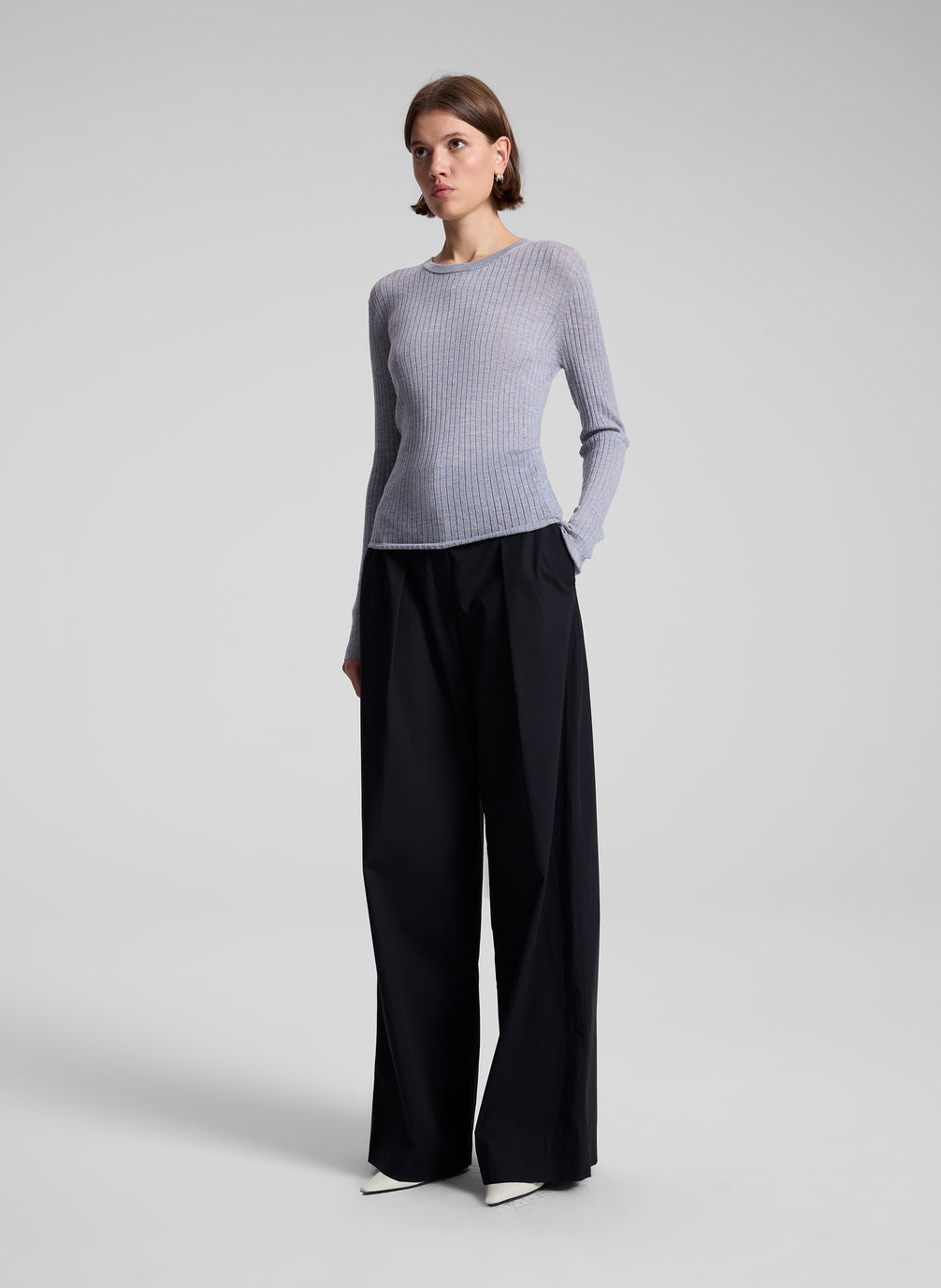 woman wearing grey long sleeve top with black wide leg pants