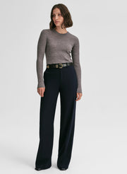 Woman wearing a gray sweater and black pants on a white background