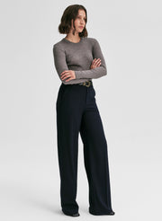 Woman wearing a gray sweater and black pants on a white background