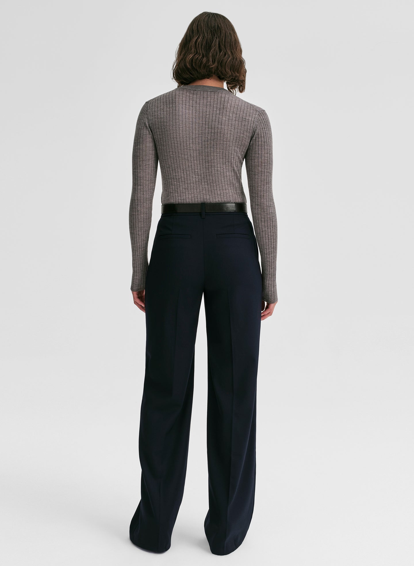 Woman wearing a gray sweater and black pants on a white background