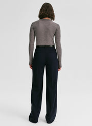 Woman wearing a gray sweater and black pants on a white background