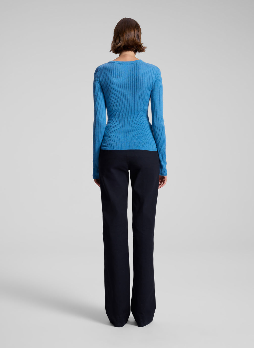 woman wearing blue knit top and black pants