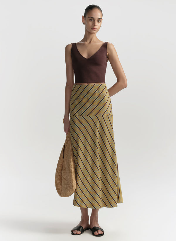 Woman wearing a brown top and striped skirt on a white background