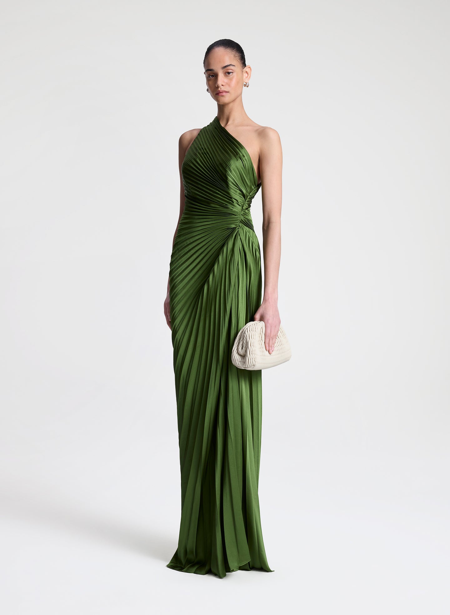Woman wearing a green one-shoulder pleated dress on a white background