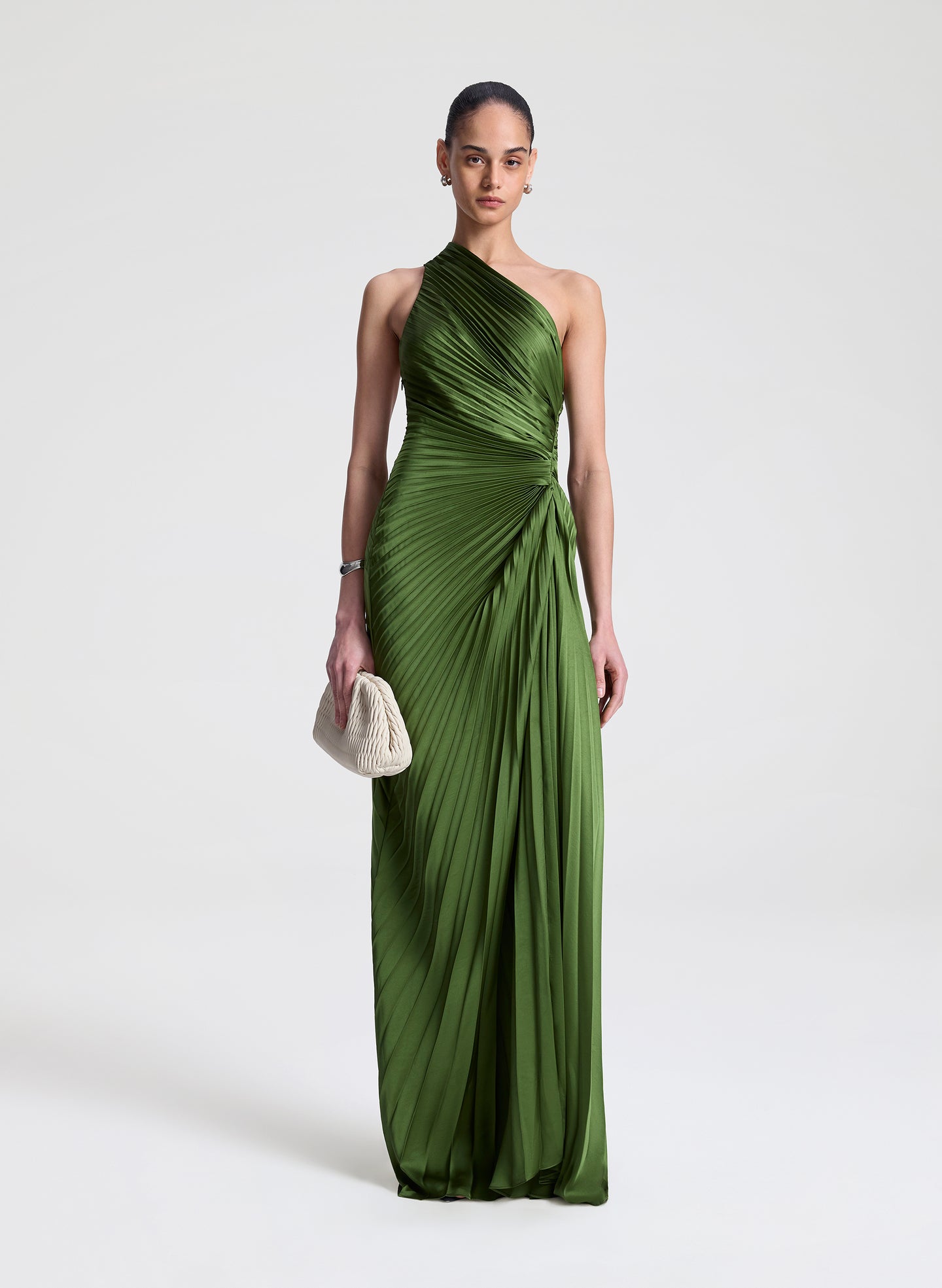 Woman wearing a green one-shoulder pleated dress on a white background