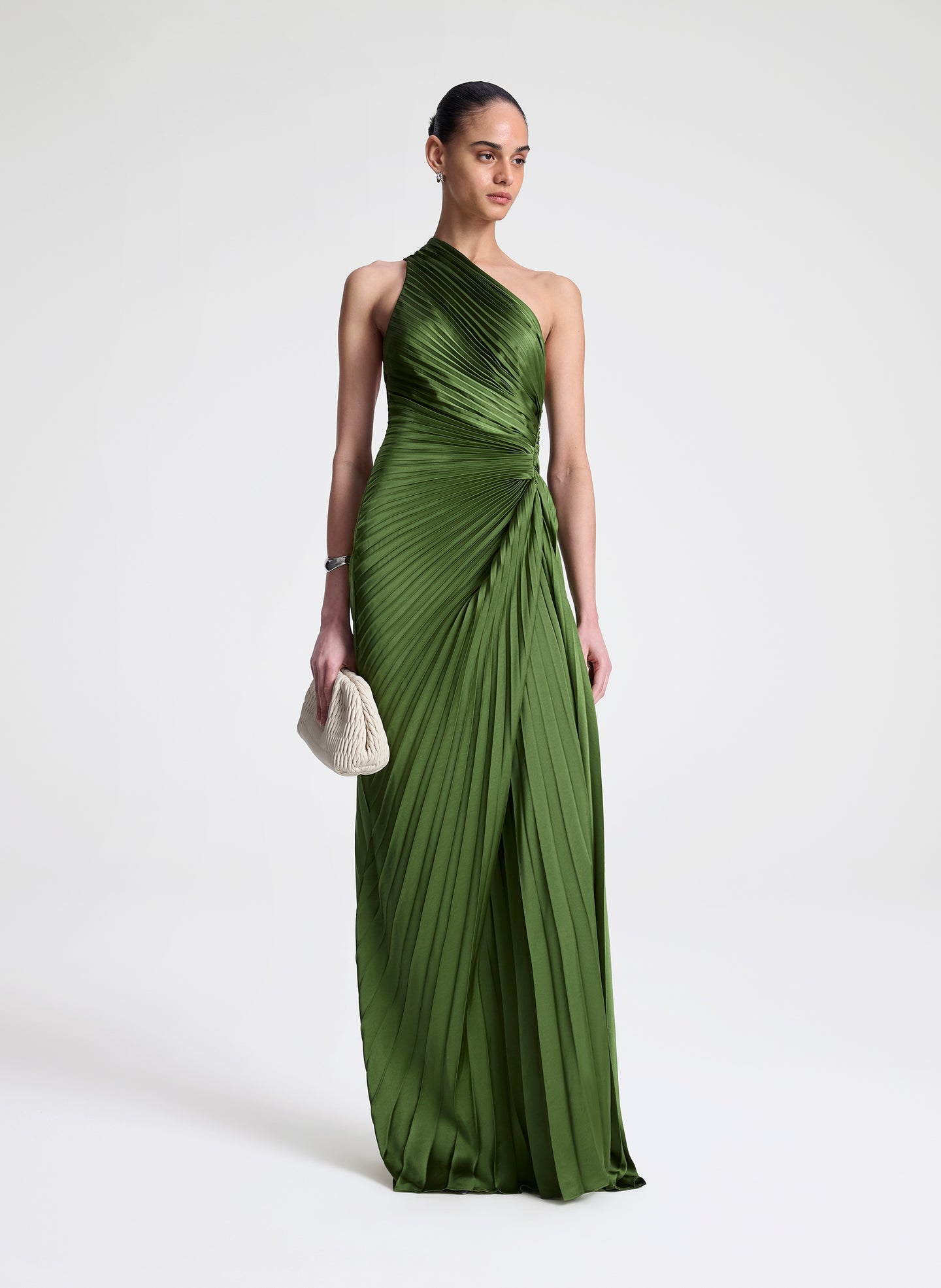 Woman wearing a green one-shoulder pleated dress on a white background