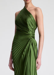 Woman wearing a green one-shoulder pleated dress on a white background